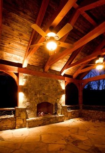 Exterior fireplace at dusk aside one of our log house plans